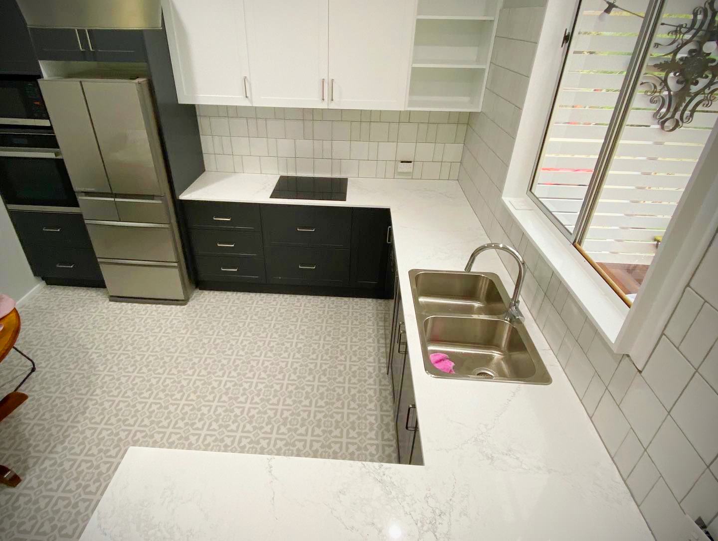 A modern, U-shaped kitchen featuring a two-tone cabinet design with black lower and white upper shaker-style cupboards.
