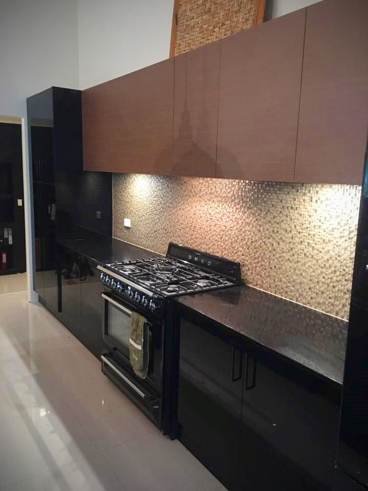 A modern kitchen featuring black lower cabinets, a black Smeg oven, and wooden upper cabinets.