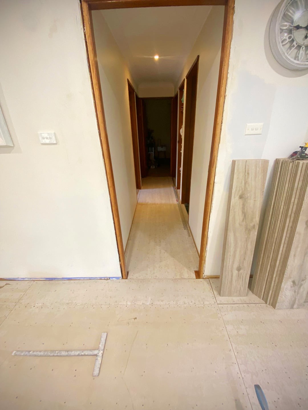 An interior shot of a home under renovation showing a hallway with light-coloured subflooring installed.