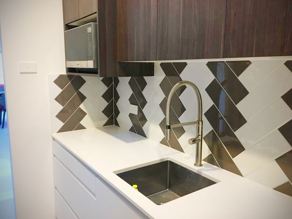 A close-up of a kitchen workspace featuring a bold brown and white chevron tile backsplash